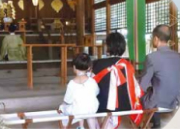 社殿で祈祷を受ける親子と、儀式を執り行う神職