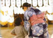 万灯祭の提灯の明かりの中、浴衣姿で子供に寄り添う女性